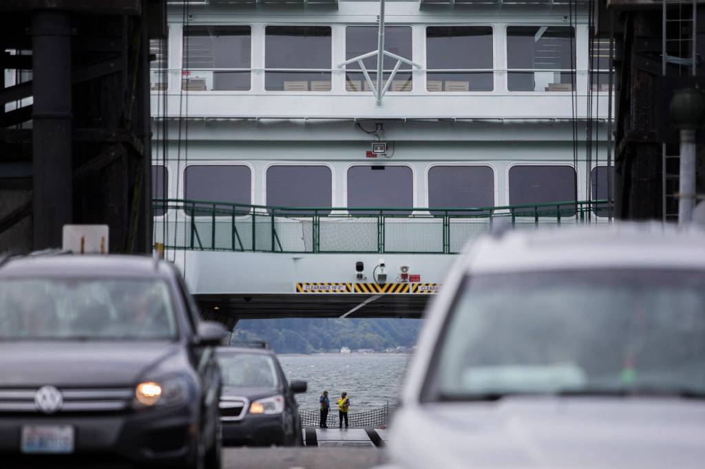 Washington State Ferries workers wait as cars offload in Mukilteo. (Olivia Vanni / The Herald)