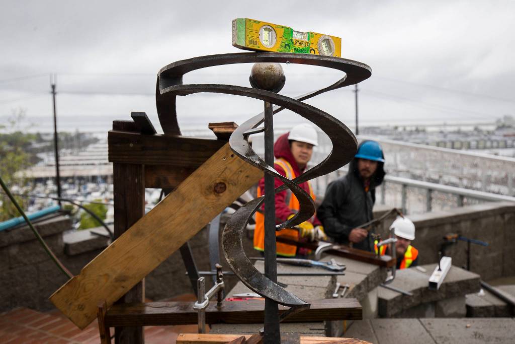 Workers from 12 Avenue Iron check a level Wednesday as they fit railings at the Grand Avenue Park Bridge in Everett. Construction on the new $20 million utility span and walkway is set to wrap by the end of July. (Andy Bronson / The Herald)