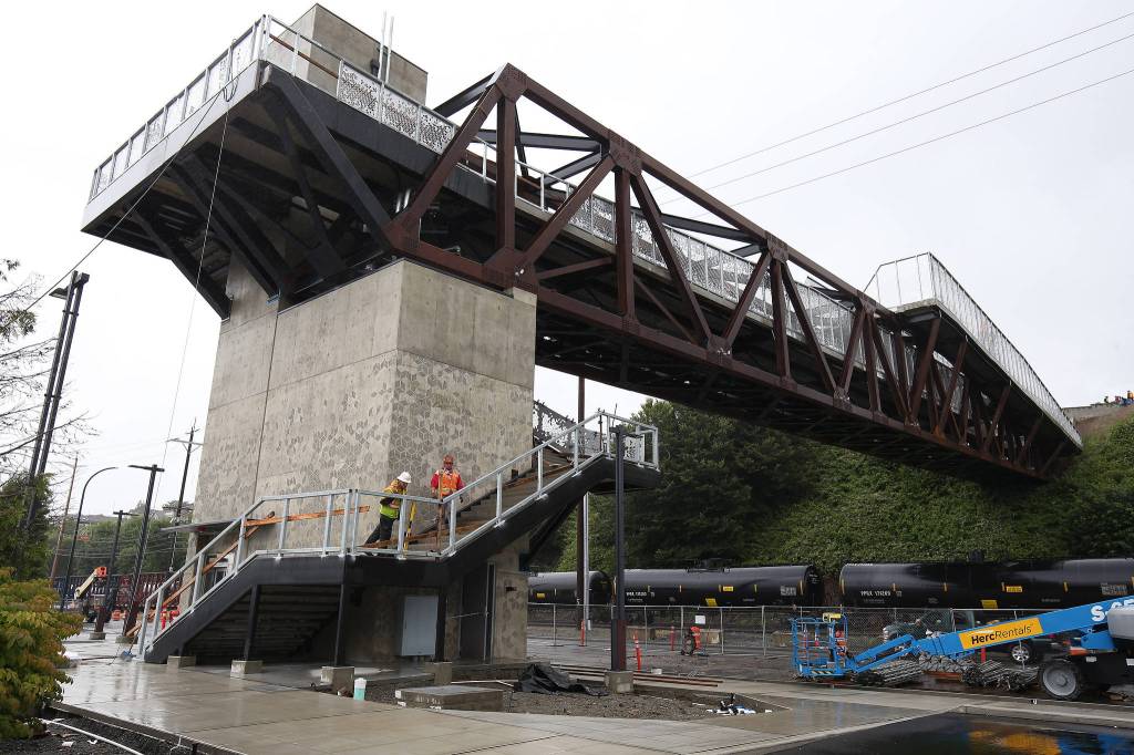 Workers install railings for the stairs at the Grand Avenue Park Bridge on Wednesday in Everett. The city expects to open the walkway this summer. (Andy Bronson / The Herald)