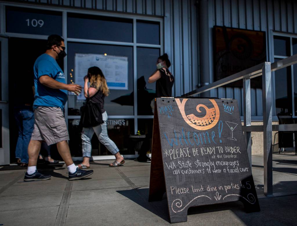 Customers wear face masks, per Washington State guidelines, as they walk in and out of Bluewater on Friday in Everett. (Olivia Vanni / The Herald)