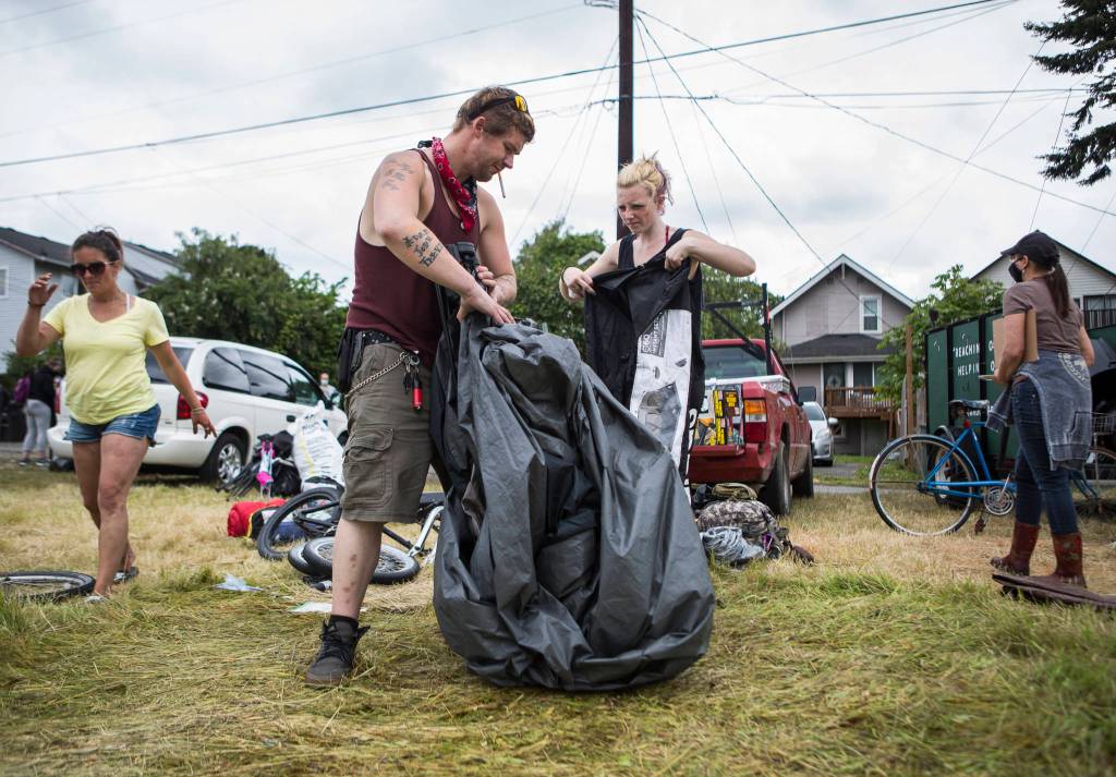 Jack Travis gets help packing up his tent at the Rucker Avenue homeless camp on Thursday in Everett. (Olivia Vanni / The Herald)