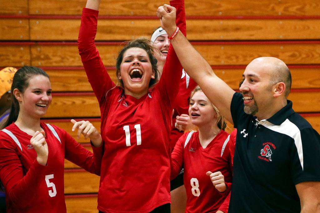 Snohomish volleyball coach Alex Tarin (right) celebrates with his team after clinching a state berth with a win over Oak Harbor on Nov. 14, 2019, at Marysville Pilchuck High School. (Kevin Clark / The Herald)