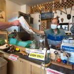 Wai Eng, owner and sandwich maker of Sub Shop, hands over a sub to a customer. Eng started the hole-in-the-wall art-covered sub shop 35 years ago in north Everett. Its a one-man, cash-only operation with 21 sandwich choices. (Andy Bronson / The Herald)