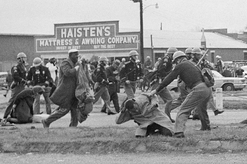 In this March 7, 1965 photo, a state trooper swings a billy club at John Lewis (right foreground), chairman of the Student Nonviolent Coordinating Committee, to break up a civil rights voting march in Selma, Alabama. Lewis sustained a fractured skull. (AP Photo/File)