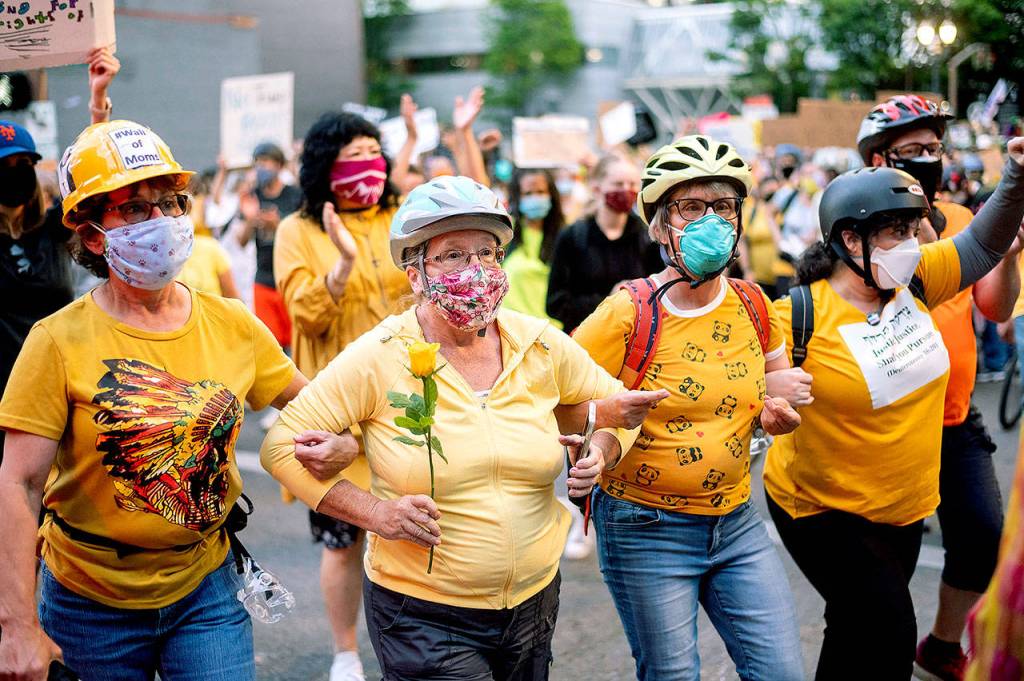 Norma Lewis holds a flower while forming a wall of moms during a Black Lives Matter protest on Monday in Portland, Oregon. (AP Photo/Noah Berger)