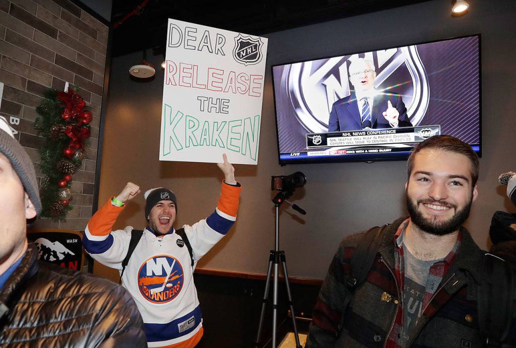 Max Rubin cheers and holds a sign in favor of the team name Kraken following the announcement of a new NHL hockey team in Seattle, at a celebratory party on Dec. 4, 2018, in Seattle. (AP Photo/Elaine Thompson)