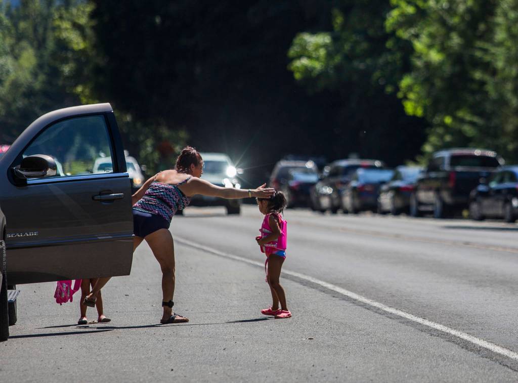 A woman reaches out to pull a young girl away from the fog line along U.S. 2 as cars speed by Wednesday in Index. (Olivia Vanni / The Herald)