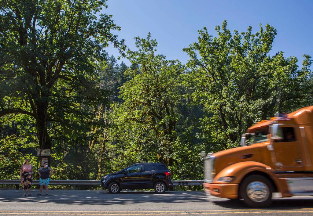 A tractor trailer speeds past parked cars and people waiting to cross U.S. 2 on Wednesday in Index. (Olivia Vanni / The Herald)