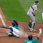 The Mariners Kyle Lewis slides safely into home as Athletics catcher Sean Murphy waits for the ball in the fourth inning of a game July 31, 2020, at T-Mobile Park in Seattle. (AP Photo/Elaine Thompson)