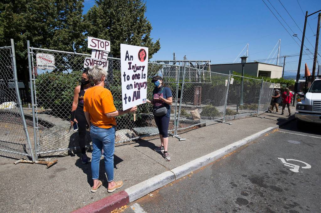 Men put up fencing at Matthew Parsons Park in Everett on Wednesday as protesters talk. (Andy Bronson / The Herald)