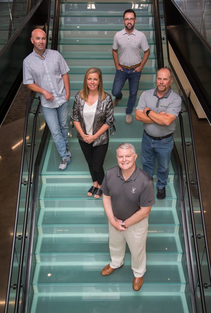 Sean Goldfinch (top), Joe Goldfinch (far left), Jenae Goldfinch (second from left), Jeff Wilson (right) and Scott Murphy (bottom) on a glass stairway at the new Goldfinch Brothers building on Beverly Park Road in Everett. (Andy Bronson / The Herald)