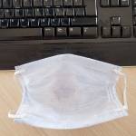 The mask of an employee who returned to the office during the normalization period after corona virus quarantine, stands in front of the keyboard. Top view. Turkey.