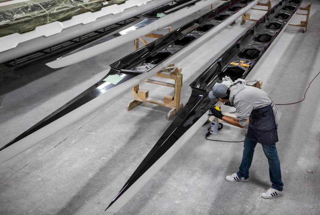 The outside of a racing shell is sanded. (Olivia Vanni / The Herald)