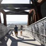 Devin and Taryn McLane appear to have the bridge to themselves as they walk dogs down the Grand Avenue Park Bridge after it opens for public use Wednesday in Everett. (Andy Bronson / The Herald)
