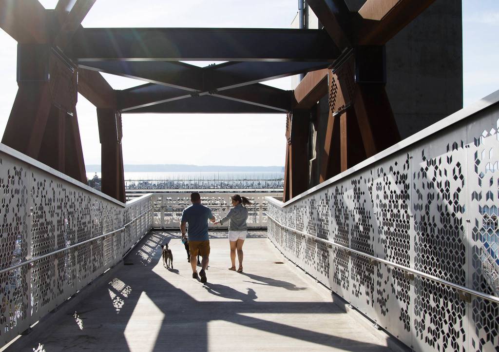 Devin and Taryn McLane appear to have the bridge to themselves as they walk dogs down the Grand Avenue Park Bridge after it opens for public use Wednesday in Everett. (Andy Bronson / The Herald)