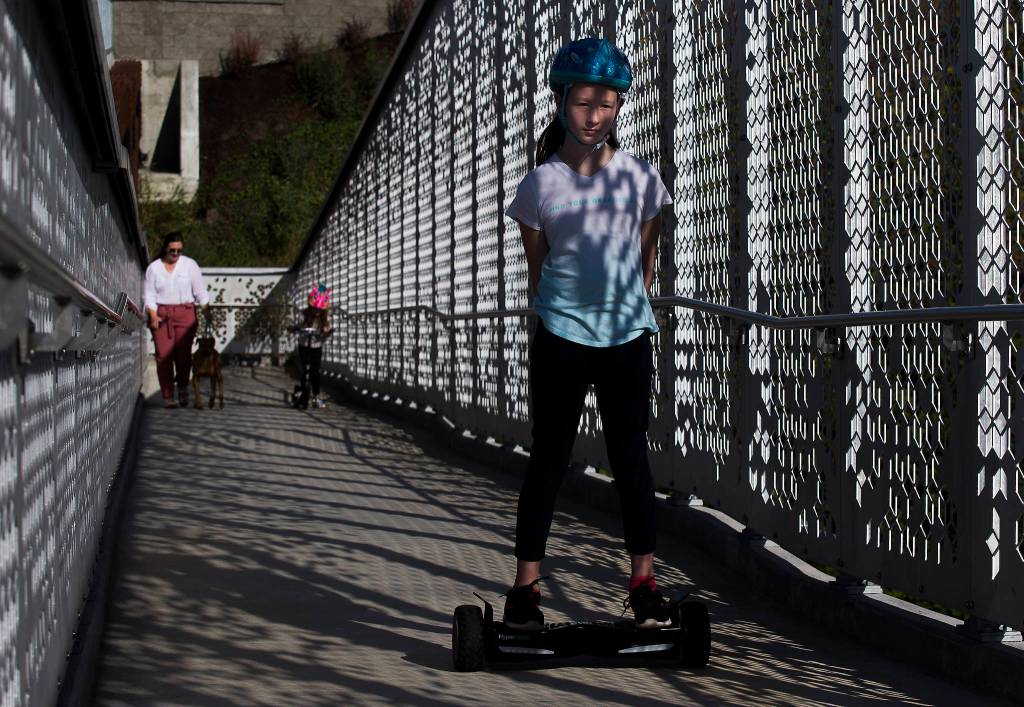 Averyn Radakovic rides her overboard up the ramp as the Grand Avenue Park Bridge opens for public use Wednesday in Everett. (Andy Bronson / The Herald)