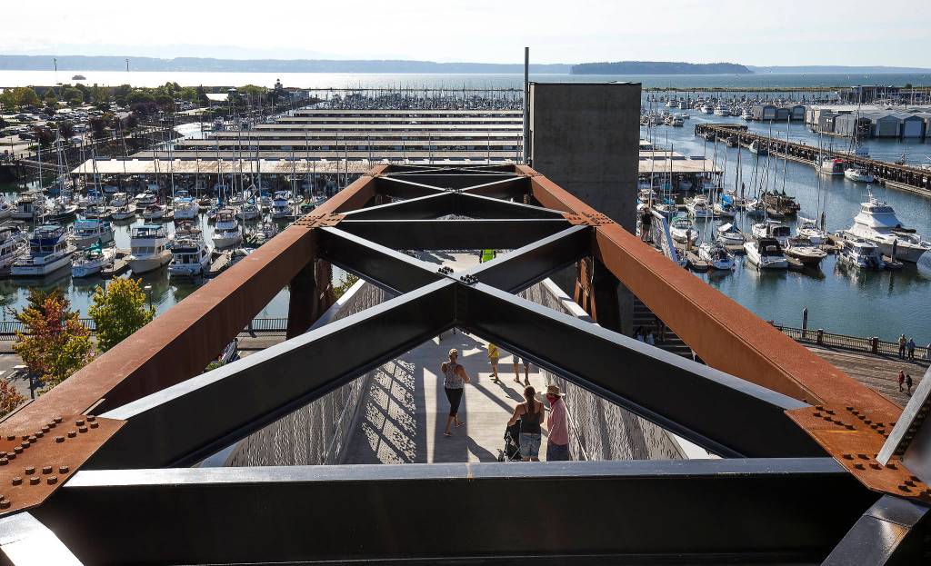 Pedestrians get a higher view of the marina as they walk along the Grand Avenue Park Bridge on Wednesday in Everett. (Andy Bronson / The Herald)