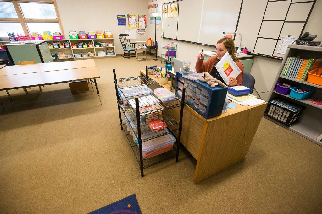 In a classroom devoid of students, first grade teacher Alyssa Jones holds up a pen and white board during an online student teacher conference at Eagle Creek Elementary on Tuesday in Arlington. (Andy Bronson / The Herald)