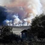 Late afternoon light catches smoke from the Cold Springs Canyon Pearl Hill Fire near a structure that appeared to be empty long before the fire on Monday near Omak. (Tyler Tjomsland/The Spokesman-Review via AP)