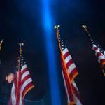 A worker removes the American flags after the ceremony as a beam of light is seen over the Pentagon, as part of the Towers of Light Tribute marking the 19th anniversary of the 9/11 attack on the Pentagon, Wednesday, in Washington. (Jose Luis Magana / Associated Press)