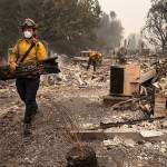 Jackson County District 5 firefighter Captain Aaron Bustard works on a smoldering fire in a burned neighborhood in Talent, Ore., Friday, Sept. 11, 2020, as destructive wildfires devastate the region. (AP Photo/Paula Bronstein)