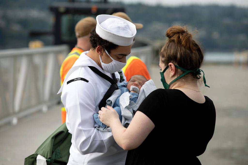A sailor meets his newborn for the first time Monday after returning from deployment at Naval Station Everett. Dozens aboard the USS Kidd were infected with COVID-19 while at sea. (U.S. Navy photo by Mass Communication Specialist 3rd Class Ethan Soto/Released)