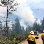 Firefighters approach the Maple Fire in Mason County in 2018 as a helicopter in the distance drops water on the blaze. (State Department of Natural Resources)
