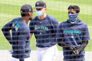 From left to right, Seattle Mariners Kyle Lewis, Kyle Seager and Dee Gordon stand together at a summer camp baseball practice in July, in Seattle. (AP Photo/Elaine Thompson)