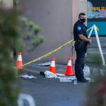 A police officer stands outside the Boo Han Oriental Market off Highway 99 in Edmonds on Tuesday, where three people were shot. (Olivia Vanni / The Herald)