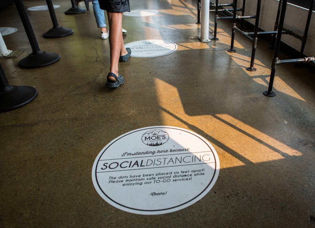 Stickers on the ground at Moes on Olympic remind customers to stay socially distanced on Sept. 30 in Arlington. (Olivia Vanni / The Herald)