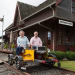 Bruce and Marie Ferguson sit on a rail car that runs along 112 feet of train tracks they installed in the yard of the Snohomish home they built to replicate a Northern Pacific train depot. (Andy Bronson / The Herald)