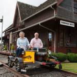 Bruce and Marie Ferguson sit on a rail car set atop train tracks in their yard at home on Tuesday, Sept. 22, 2020 in Snohomish, Washington.  The Ferguson's built in their home in 2007 to mimic a Northern Pacific train depot. (Andy Bronson / The Herald)