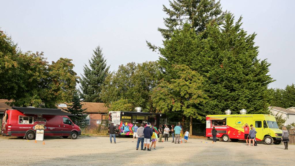 People gather in a parking lot to sample food truck offerings on Beverly Blvd. in Everett on Oct. 1. (Kevin Clark / The Herald)
