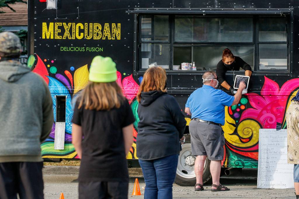 People gather in a parking lot to sample food truck offerings on Beverly Blvd. in Everett on Oct. 1. (Kevin Clark / The Herald)
