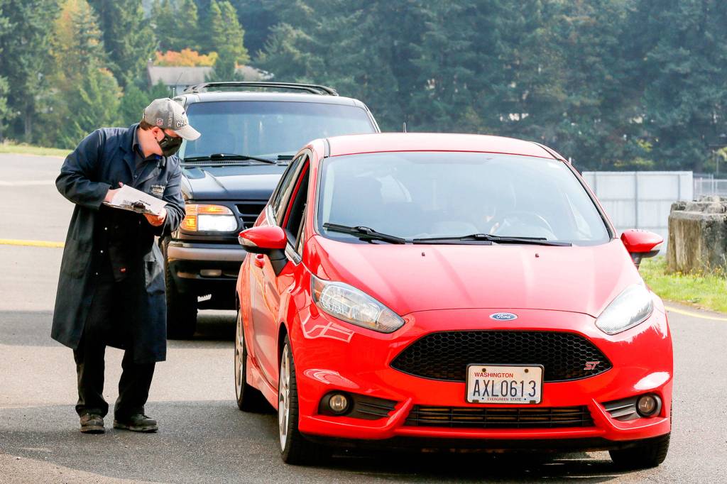 Bryan Robbins check off students picking up equipment class at Meadowdale High School in Lynnwood on Oct. 1, 2020. (Kevin Clark / The Herald)