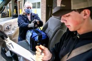 Kellie Shanahan loads Jacob McGovern's vehicle with his class tool bag at Meadowdale High School in Lynnwood on October 1, 2020.  (Kevin Clark / The Herald)