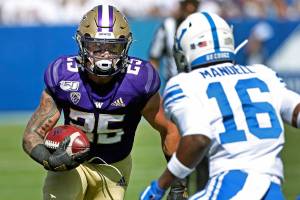 Washington running back Sean McGrew (25) runs the ball as BYU defensive back D'Angelo Mandell (16) tracks him down during the first half of an NCAA college football game, Saturday, Sept. 21, 2019, in Provo, Utah. (AP Photo/George Frey)