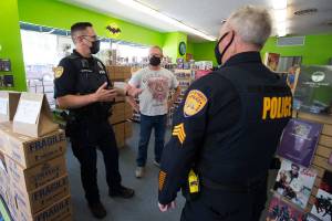 Everett Comics owner Charlie Knoedler and his wife Tracy talk with Everett Police Officers as they drop by to talk about the recent theft of a 4-foot tall Funko Batman Statue on Monday, Oct. 5, 2020 in Everett, Washington.  The statue was stolen in a “smash and grab” early Sunday. (Andy Bronson / The Herald)