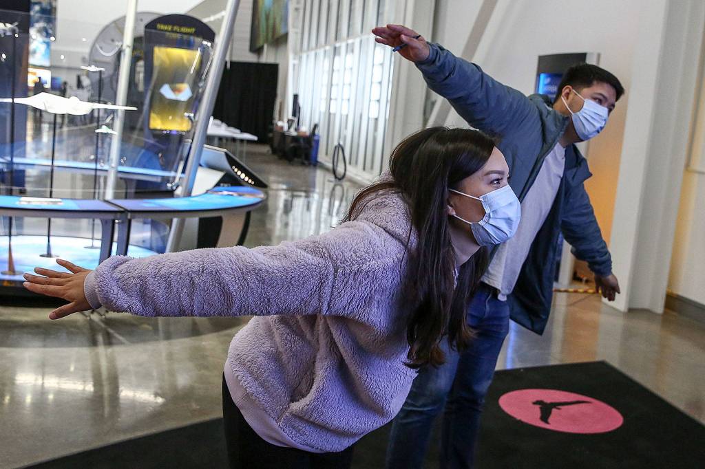 Nina Dung (left) and Andrew Hwang participate in a birds-in-flight simulation Thursday at the Boeing Future of Flight in Mukilteo at Paine Field. (Kevin Clark / The Herald)