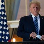 President Donald Trump holds his face mask as he stands on the Blue Room Balcony upon returning to the White House Monday, Oct. 5, 2020, in Washington, after leaving Walter Reed National Military Medical Center, in Bethesda, Md. Trump announced he tested positive for COVID-19 on Oct. 2. (AP Photo/Alex Brandon)