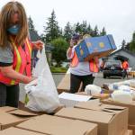 Lisa Naasz (left) and Lesli Gisvold load boxes for distribution Friday morning at the Faith Food Bank at Faith Lutheran Church in Everett on October 9, 2020. (Kevin Clark / The Herald)