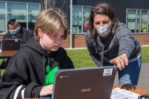 Fifth grader Vivian Fisher get help setting up a ChromeBook from Jody Urban at Frank Wagoner Elementary on Wednesday, April 8, 2020 in Monroe, Wa. Students of Frank Wagoner Elementary School returned on Wednesday to collect computers and other supplies to finish up the rest of the school year at home. (Andy Bronson / The Herald)