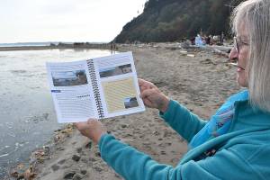 Jeanie McElwain holds the new edition of “Getting to the Water’s Edge,” a book that includes information about beach accessibility, fishing spots, natural history, species identification and more, including all of the sea creatures that can be found at Double Bluff in South Whidbey. (Emily Gilbert / Whidbey News-Times)