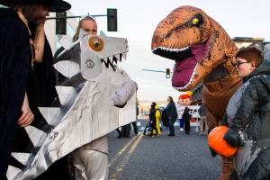 People in dinosaur costumes greet each other during Downtown Trick-or-Treating on Oct. 31, 2019 in Everett, Wash. Health officials have discouraged trick-or-treating this year. (Olivia Vanni / The Herald)