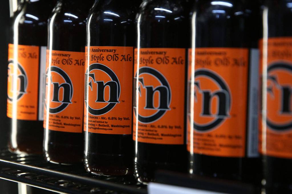 Bottles of Foggy Noggin Brewings Anniversary English Style Ole Ale line a shelf at the brewery in Bothell. (Kevin Clark / The Herald)