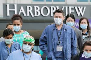 Health care workers and other staff walk out of Harborview Medical Center, a part of UW Medicine, during a noon hour break in a demonstration asking management to do more to protect staff, patients and the public amid the COVID-19 pandemic, Thursday, May 14, 2020, in Seattle.  (AP Photo/Elaine Thompson)
