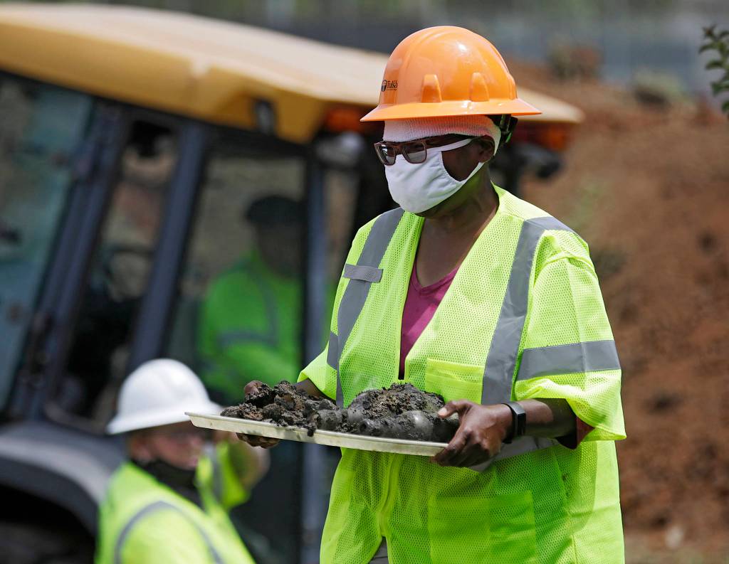 FILE - In this July 21, 2020, file photo, forensic anthropologist Phoebe Stubblefield carries a tray of items found at Oaklawn Cemetery during a test excavation in the search for possible mass graves from the 1921 Tulsa Race Massacre in Tulsa, Okla. A second excavation begins Monday, Oct. 19, 2020 at a Tulsa cemetery in search of people killed in the massacre in an effort to identify the victims and shed light on the violence. (Mike Simons/Tulsa World via AP File)