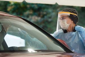 Volunteer registered nurse Stephanie Hamilton recieves a swab from a driver as she works at a Covid-19 testing site in the parking lot at Everett Memorial Stadium on Tuesday, Oct. 20, 2020 in Everett, Washington.  (Andy Bronson / The Herald)