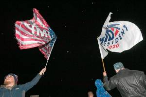 On West 12th Street across from the Erie International Airport, Steven Lantz-Gordon, 24, at left, of Harborcreek Township, waves a flag in support of President Donald Trump near David Oberg, 60, at right, of Grand Valley, who raises a flag in support of Democratic presidential candidate and former Vice President Joe Biden during a rally held by Trump, Tuesday, Oct. 20, 2020, at Erie International Airport, Tuesday, Oct. 20, 2020, in Millcreek Township, Pa. (Christopher Millette/Erie Times-News via AP)