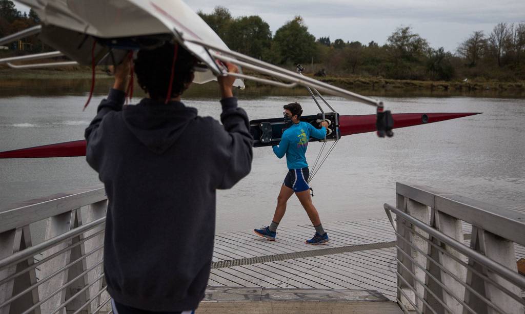 Everett Rowing Association rower Owen Moody, 17 (right) carries his single scull to the water. (Andy Bronson / The Herald)